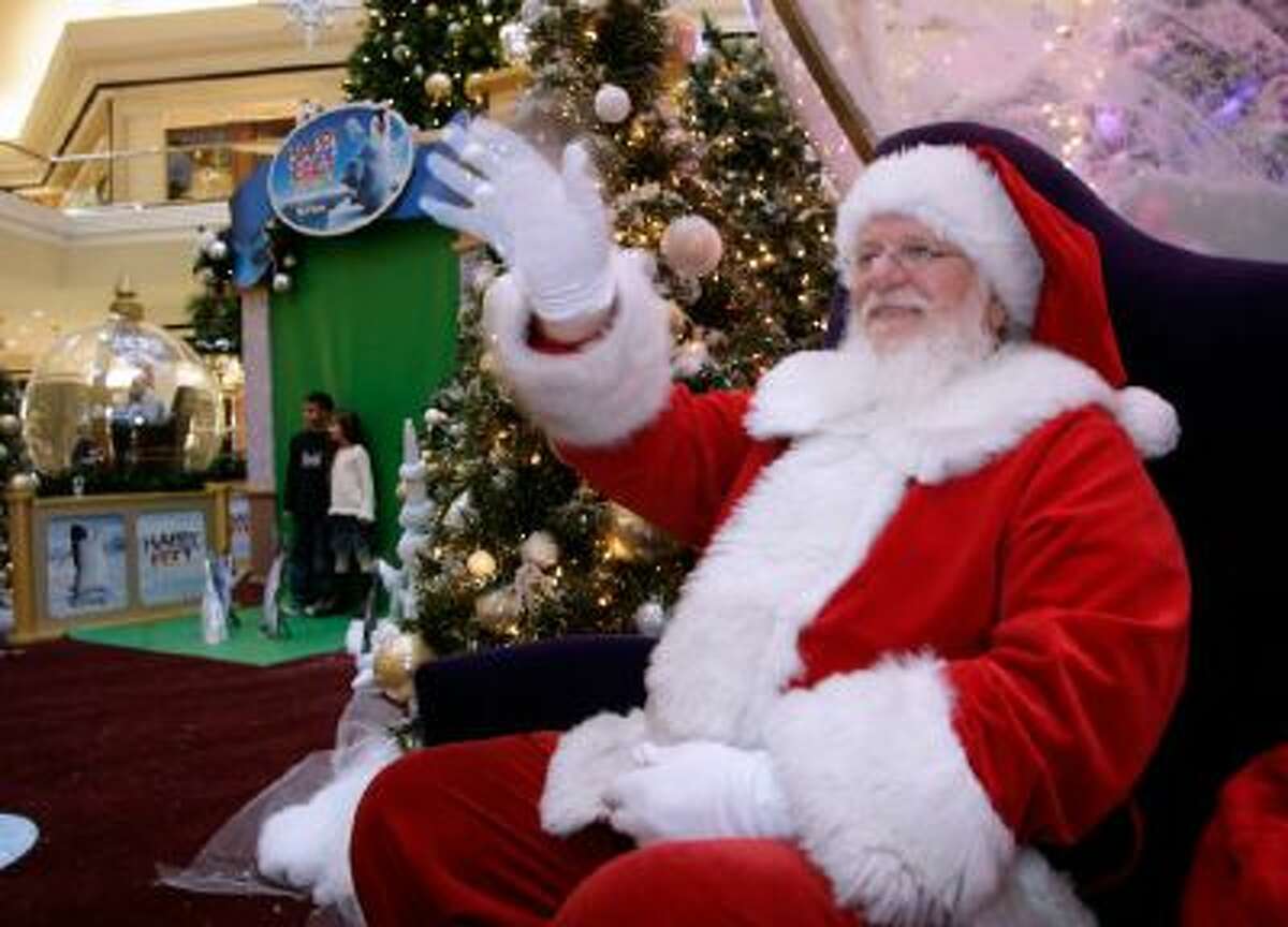 A man dressed as Santa Claus waves to holiday well-wishers while waiting for children to visit his meeting place in the Cherry Creek Shopping Center in Denver.