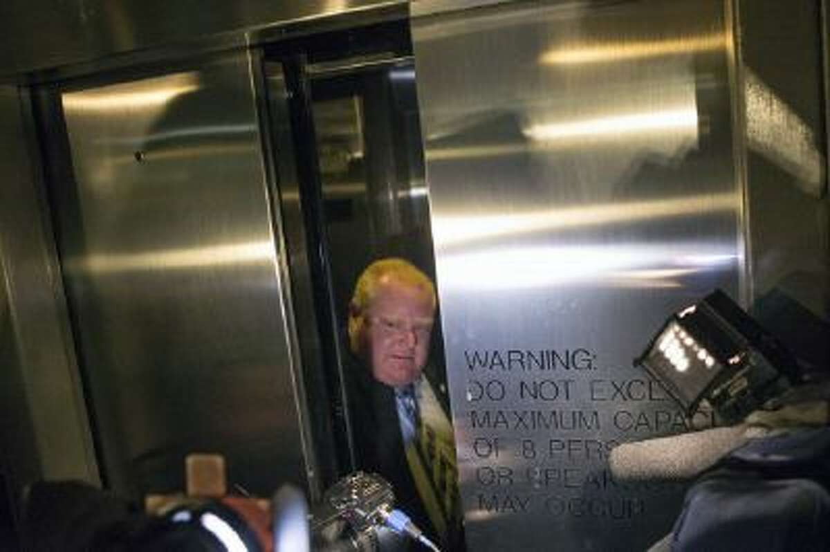 In this Wednesday, Nov. 13, 2013 file photo, reporters and photographers follow Mayor Rob Ford as he rides in an elevator before a City Council debate in Toronto.