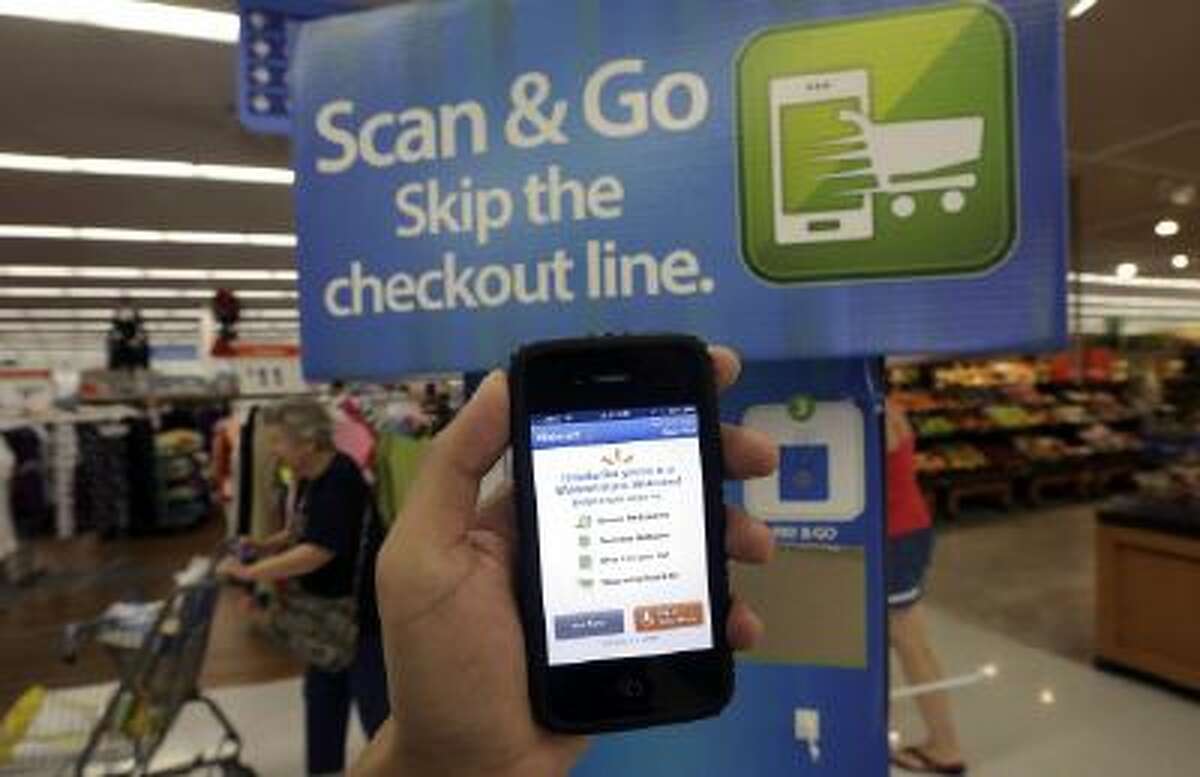 In this Sept. 19, 2013 photo, a Wal-Mart representative demonstrates a Scan & Go mobile application on a smartphone at a Wal-Mart store in San Jose, Calif.
