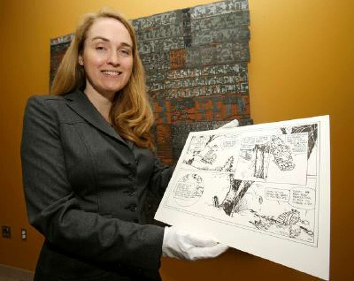 In this Wednesday, Oct. 23, 2013 photo, Juli Slemmons holds a "Calvin and Hobbes" comic by cartoonist Bill Watterson at the Billy Ireland Cartoon Library & Museum in Columbus, Ohio.