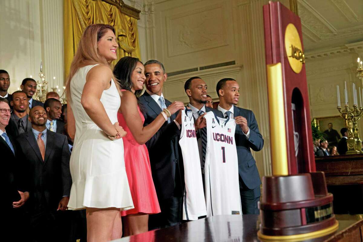 Stefanie Dolson, left, and Bria Hartley, and men’s players Ryan Boatright, and Shabazz Napier, give jerseys to President Barack Obama.