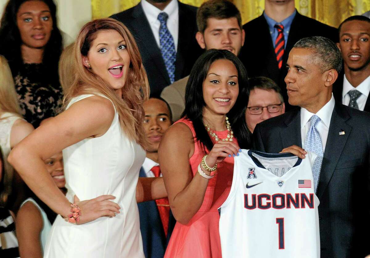 Stefanie Dolson, left, smiles for the audience with President Barack Obama. Teammate Bria Hartley holds part of the jersey, center. (AP Photo/Susan Walsh)