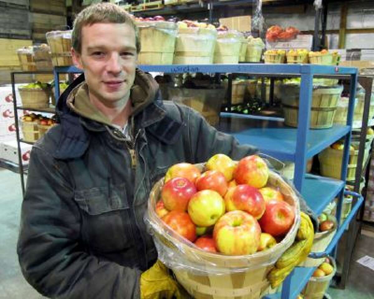 In this photo taken Nov. 7, 2013, Mark Schiller, farm operations manager of King Orchards in Central Lake, Mich., holds a half-bushel basket of Honeycrisp apples inside the warehouse where they are washed and prepared for shipment to markets.