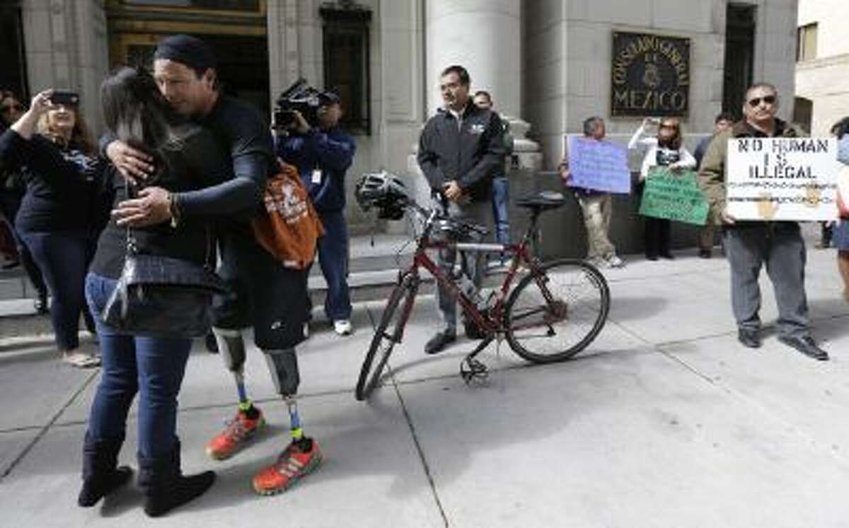 Cyclist Carlos Gutierrez, a double amputee, center, gets a hug from a supporter during a stop at the Mexican Consulate, Thursday, Nov. 7, 2013, in San Antonio.