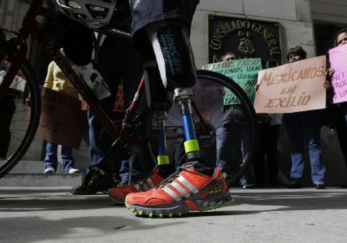 Cyclist Carlos Gutierrez, a double amputee, center, stands with his bike during a stop at the Mexican Consulate, Thursday, Nov. 7, 2013, in San Antonio.