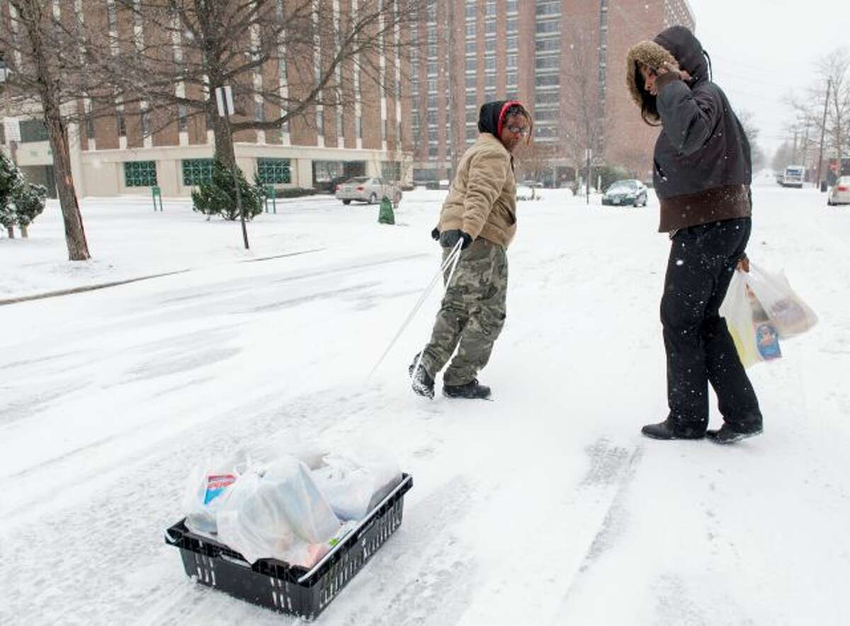 Shaquella Newby, 21, right, looks back as her partner Brittany Bigby, 25, pulls a make-shift sled full of groceries to their home, from a grocery store in Alexandria, Va., Monday, March 3, 2014. The National Weather Service has issued a Winter Storm Warning for the greater Washington Metropolitan region, prompting area schools and the federal government to close for the wintry weather. (AP Photo/Cliff Owen)
