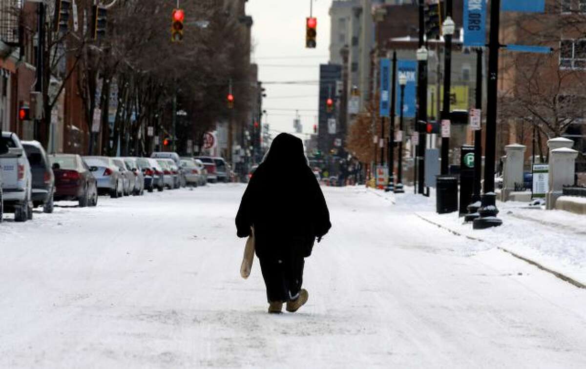 A pedestrian walks in the middle of a snow covered street, Monday, March 3, 2014, in downtown Cincinnati. The area received from three to six inches of new snow. (AP Photo/Al Behrman)