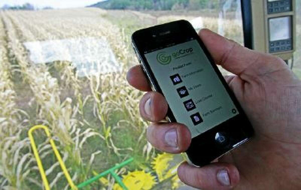In this Oct. 21, 2013 photo, Tony Pouliot demonstrates the goCrop app on his mobile photo in the cab of his combine on his farm in Westford, Vt.