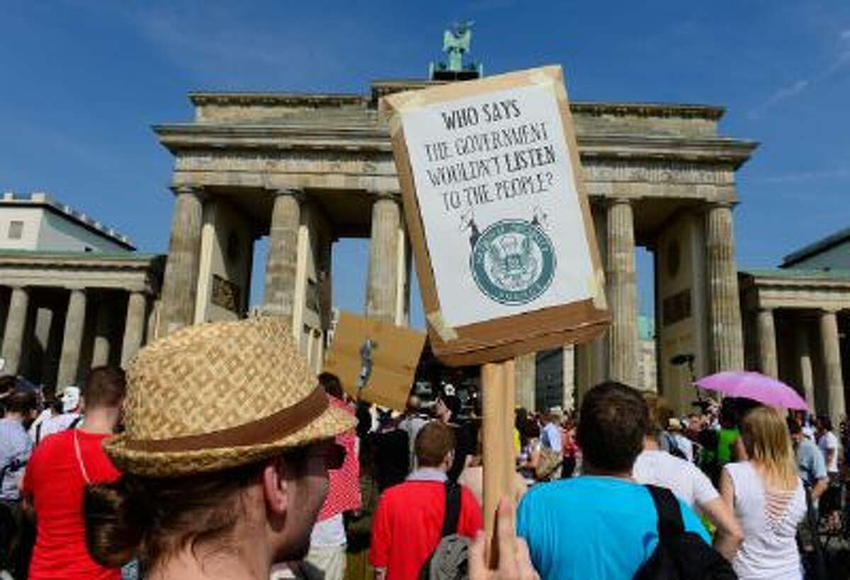 Demonstrators hold up banners as they take part in a protest in front of Berlin's landmark Brandenburg Gate against the US National Security Agency (NSA) collecting German emails, online chats and phone calls and sharing some of it with the country's intelligence services in Berlin on July 27, 2013.
