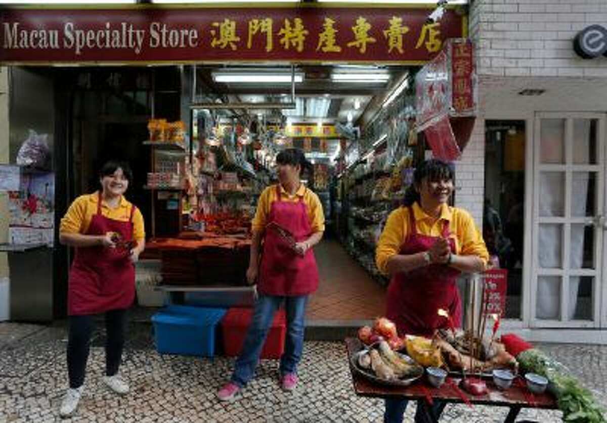 In this Feb. 1, 2014 photo, shop clerks place the offering to the God in front of a local product shop during a Chinese New Year celebration in Macau.