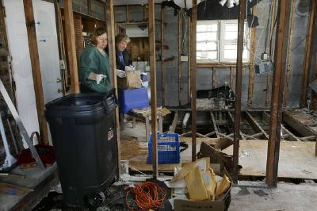 Lee Ann Newland and husband John Lambert, sort through items, inside their Superstorm Sandy damaged home near the Shark River in Neptune, N.J., Sunday, Oct. 13, 2013.