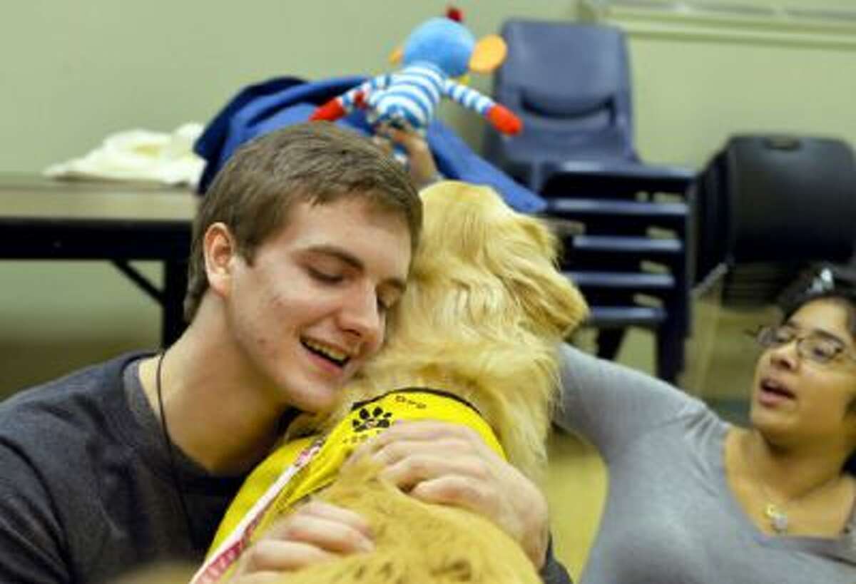 York College senior Mickey Collins hugs golden retriever Darby as freshman Erin Baker tempts Darby with a dog toy on Wednesday in the student union at York College in York, Penn.