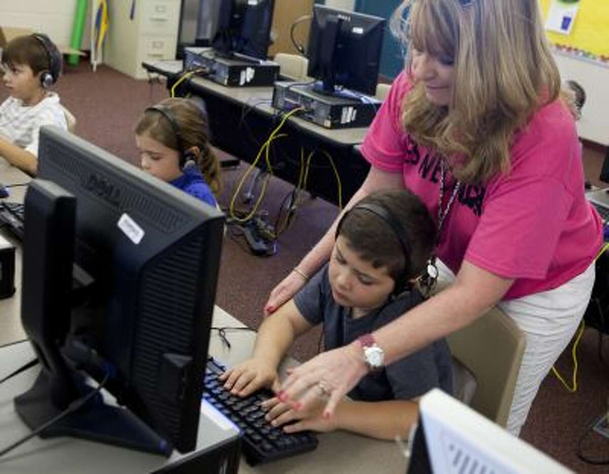 Second-grade teacher Kimberly Blackert helps Cody Simpson with his touch typing assignment on Oct. 11, 2013 at Horseshoe Trails Elementary School in Phoenix, Ariz. Formal keyboarding instruction at the school began this year for second-graders, and is being taught in other schools as early as kindergarten.