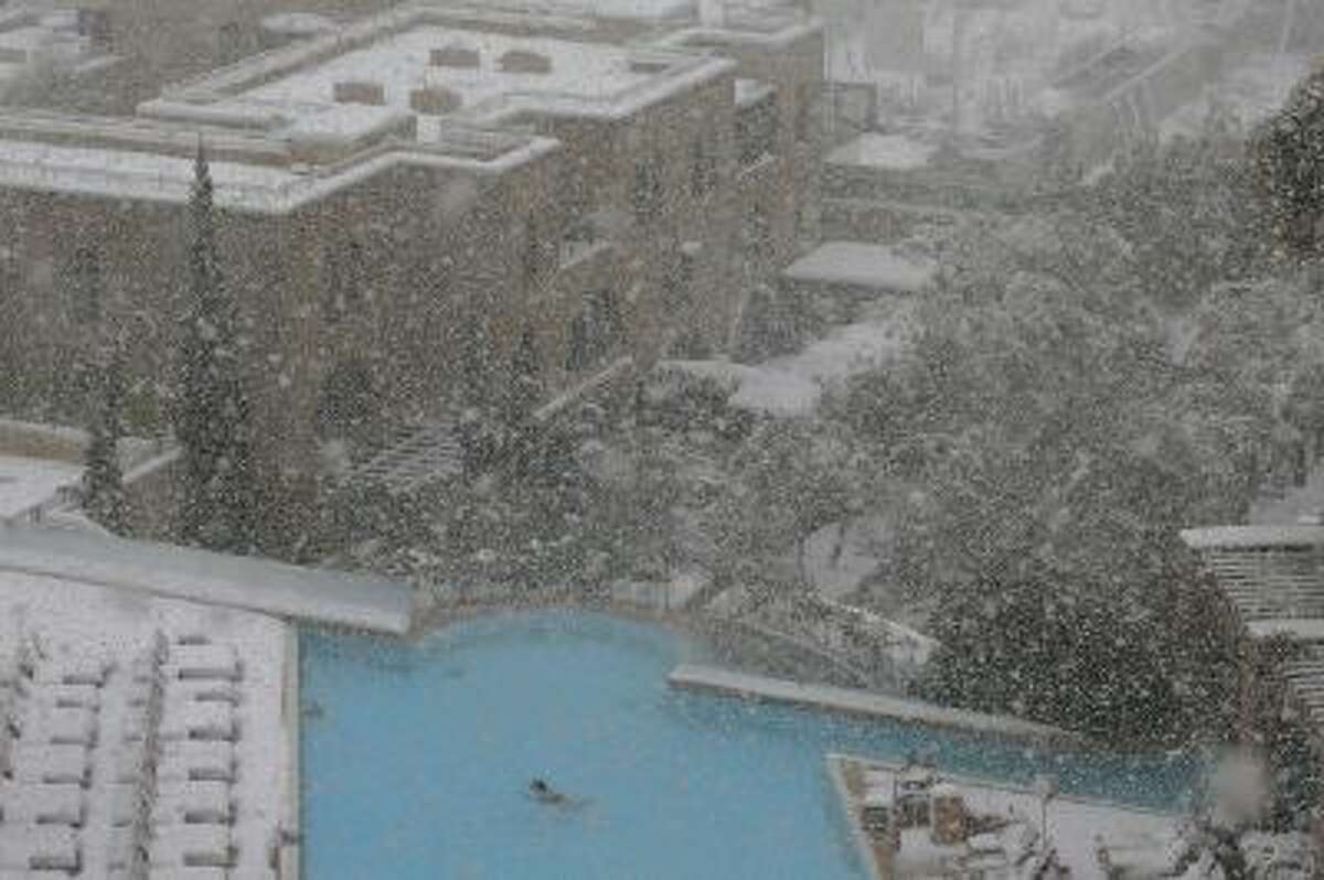 A woman swims in the pool at the David Citadel Hotel during a snowstorm in Jerusalem Friday, Dec. 13, 2013.