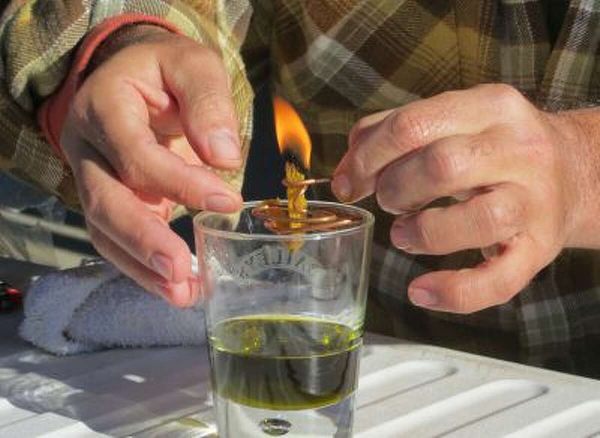 In this Oct. 5, 2013 photo, Derek Cross, a chef who specializes in cooking with hemp, demonstrates the burning properties of hemp oil, which he touts as a digestible bio fuel, during the first known harvest of industrial hemp in the U.S. since the 1950s, at a farm in Springfield, Colo.