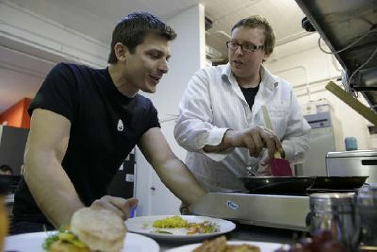 In this photo taken Tuesday, Dec. 3, 2013, CEO Josh Tetrick, left, watches as research and development chef Trevor Niekowal, right, makes a plant-based scrambled egg at Hampton Creek Foods in San Francisco.