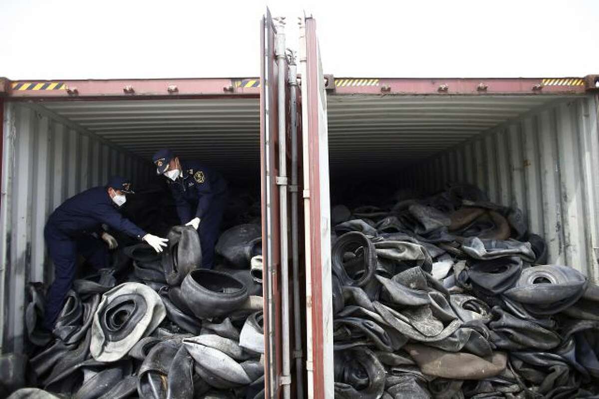 In this photo taken April 11, 2013, Chinese customs officials check a container of illegally imported used tires in Shanghai. China for years has welcomed the world's trash, creating a roaring business in recycling and livelihoods for tens of thousands. Now authorities are clamping down on an industry that has helped the rich West dispose of its waste but also added to the degradation of China's environment. (AP Photo) CHINA OUT