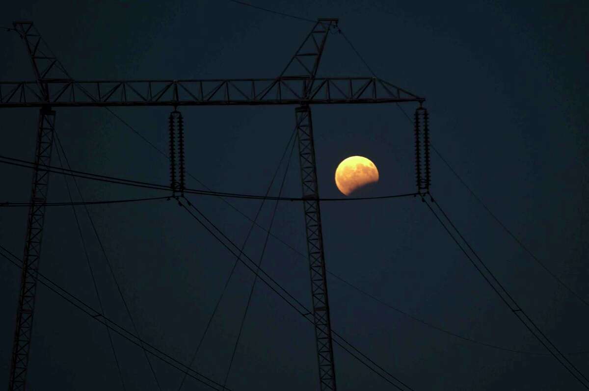 The first penumbral eclipse of moon of 2017 seen behind the electric power transmission lines in Lipjan, Kosovo on Monday, Aug. 7, 2017 (AP Photo/Visar Kryeziu)
