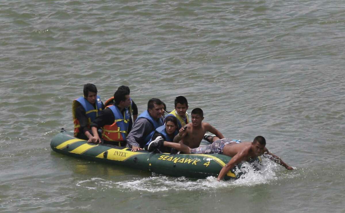 JUNE 24, 2014, 2:02 PM, ROMA, TEXAS - Using an inflatable raft, coyotes, or smugglers, carry immigrants across by the international bridge on the Rio Grande in Roma, Texas. According to law enforcement officials, higher risk smuggling operations have moved into Starr County in order to avoid the saturated border in Hidalgo, County.