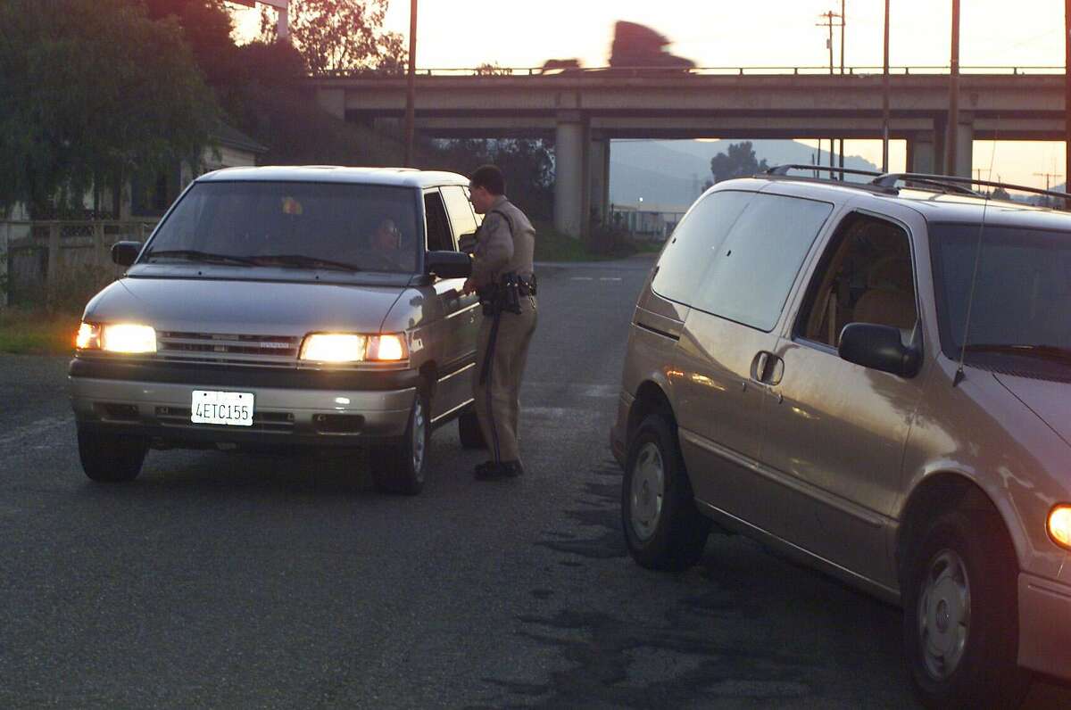 CODELIAXX-11-C-04JAN01-CZ-KW - While traffic passes on I680 (background), CHP officer Tony Blencowe (CQ) pulls over traffic law offenders two at a time to ticket them for making an illegal right turn onto the residential street of Bridgeport Avenue where commuters that have used the frontage road to avoid the i680/i80 interchange try to use the residential street to further shorten the short cut. SAN FRANCISCO CHRONICLE PHOTO BY KAT WADE