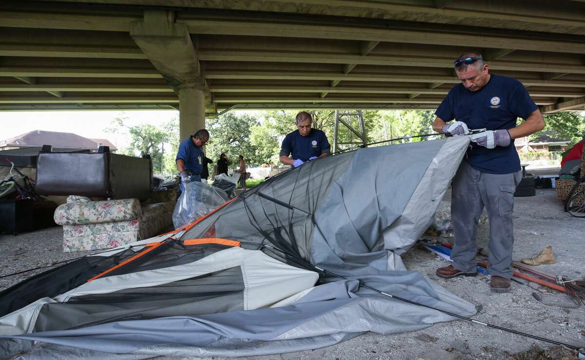 Miguel Mendoza, left to right, Robert Lam, and Alejandro Canton with the City of Houston General Service Department break down a tent that was left behind as officials evacuated a homeless encampment due to serious health hazards under the Highway 59 overpass, between Caroline and La Branch streets Thursday, Aug. 10, 2017, in Houston. People will be able to return once the city is done with cleanup of the area. ( Godofredo A. Vasquez / Houston Chronicle )