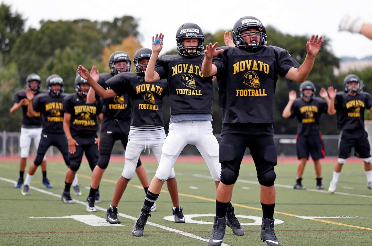 Novato High School football freshman Jackson Gremmels (center) joins teammates in calisthenics during practice in Novato, Calif. on Thursday, August 3, 2017.