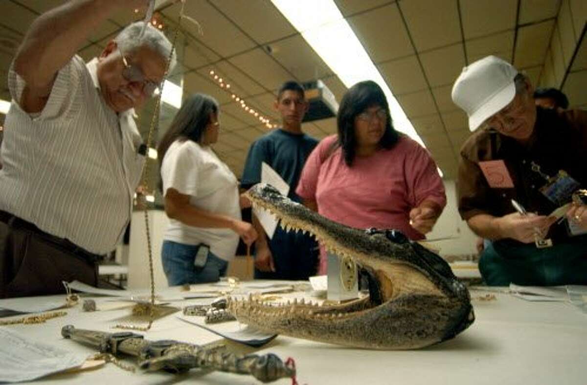 People examine items for auction, including a alligator head, prior to the start of the SAPD Forfeiture Auction held Thursday Oct. 2, 2003 at the VFW Hall, 650 VFW Blvd. PHOTO BY EDWARD A. ORNELAS
