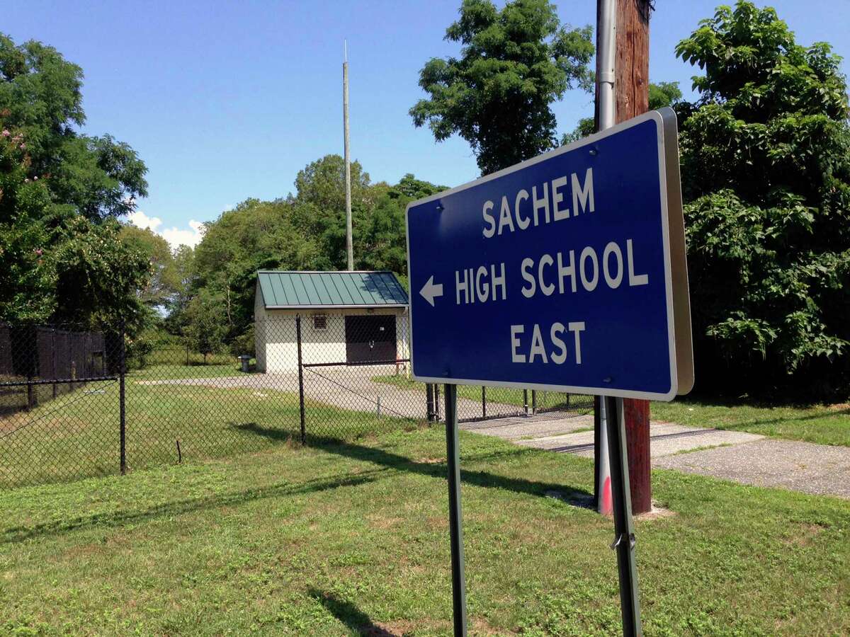A sign points to Sachem East High School in Farmingville, N.Y. where police say log fell on a teenage football player's head, killing him, Thursday Aug. 10, 2017. Joshua Mileto, 16, was participating in a pre-season drill with a group of high school football players, carrying a large log overhead for a workout, when the wood fell on his head. The 11th-grader was taken from the school to Stony Brook University Hospital, where he was pronounced dead. (AP Photo/Frank Eltman) ORG XMIT: RPFE101