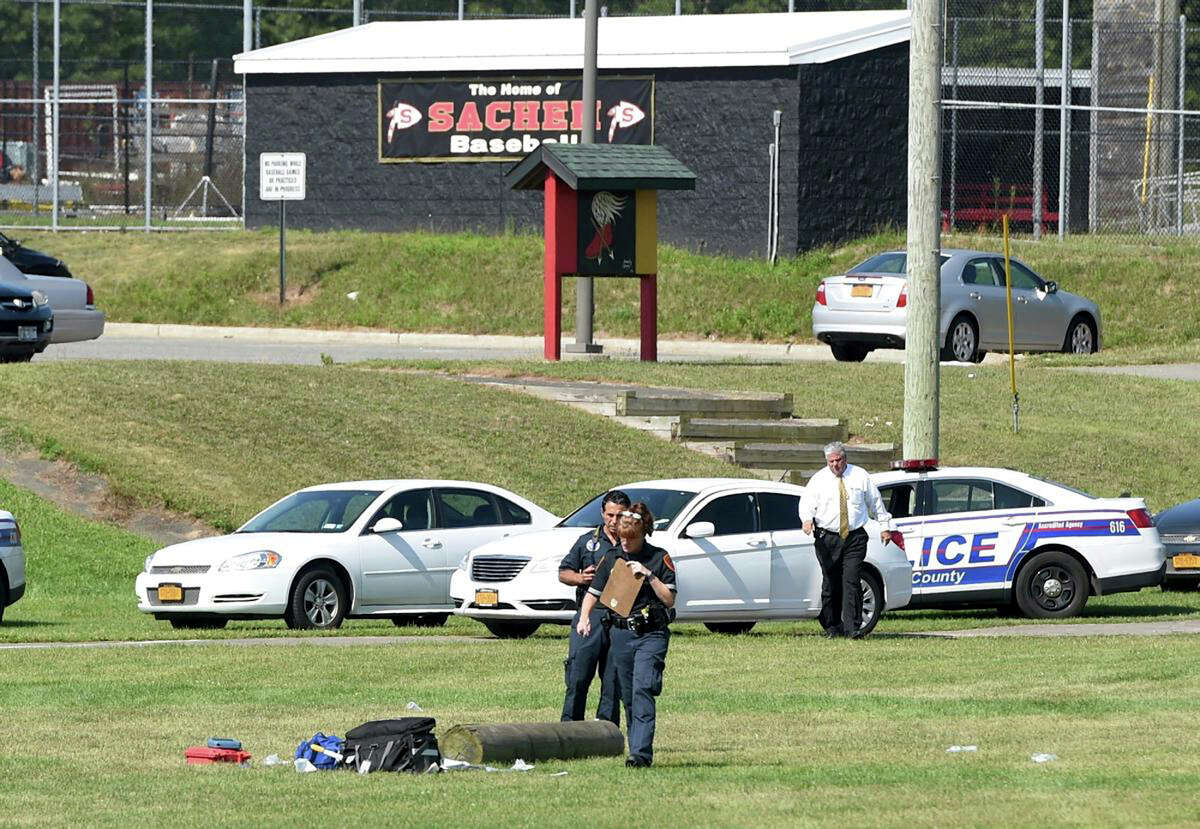 Suffolk County police work on the athletic field at Sachem High School East in Farmingville, N.Y., where a teenage football player was fatally injured during a drill earlier in morning, Thursday, Aug. 10, 2017. Police say Joshua Mileto, 16, was participating in a pre-season drill with a group of high school football players, carrying a large log overhead for a workout, when the wood fell on his head. The 11th-grader was taken from the school to Stony Brook University Hospital, where he was pronounced dead. (James Carbone/Newsday via AP) ORG XMIT: NYANE201
