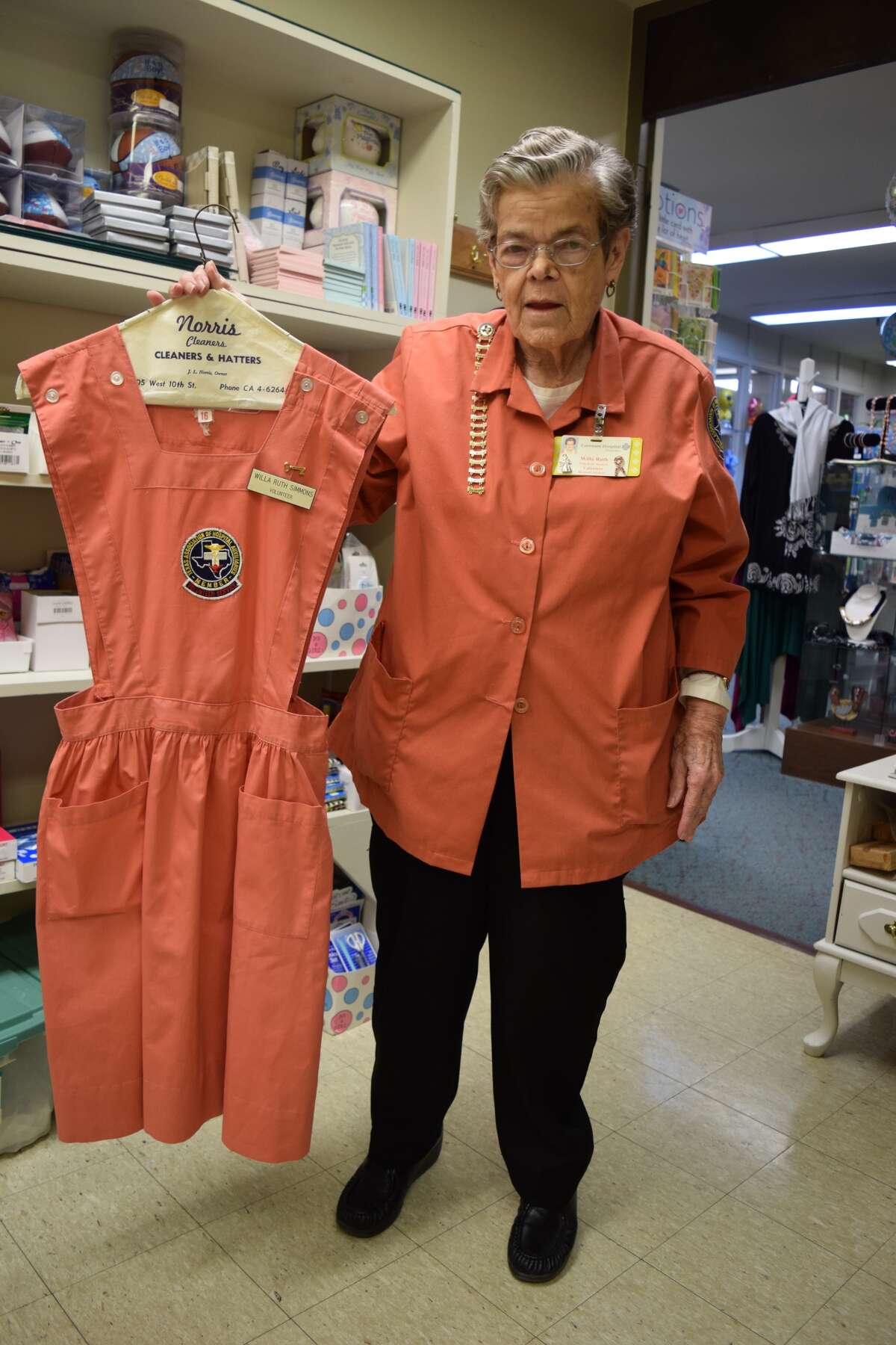 Longtime Hospital Auxiliary member Willa Ruth Simmons displays an old Pink Lady’s uniform while wearing her more modern smock. She has volunteered at the hospital for almost 50 years.