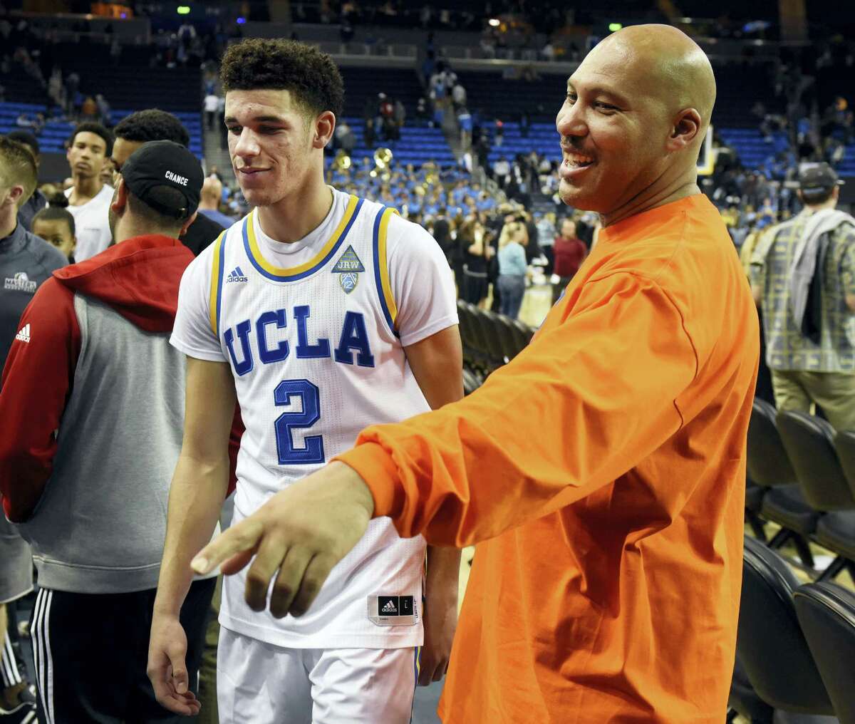 In this Nov. 20, 2016 photo, UCLA’s Lonzo Ball (2) walks by his father LaVar Ball, right, to greet family members after UCLA defeated Long Beach State in an NCAA college basketball game in Los Angeles. By now the entire basketball world knows Lonzo Ball is a singular talent with a unique parent.