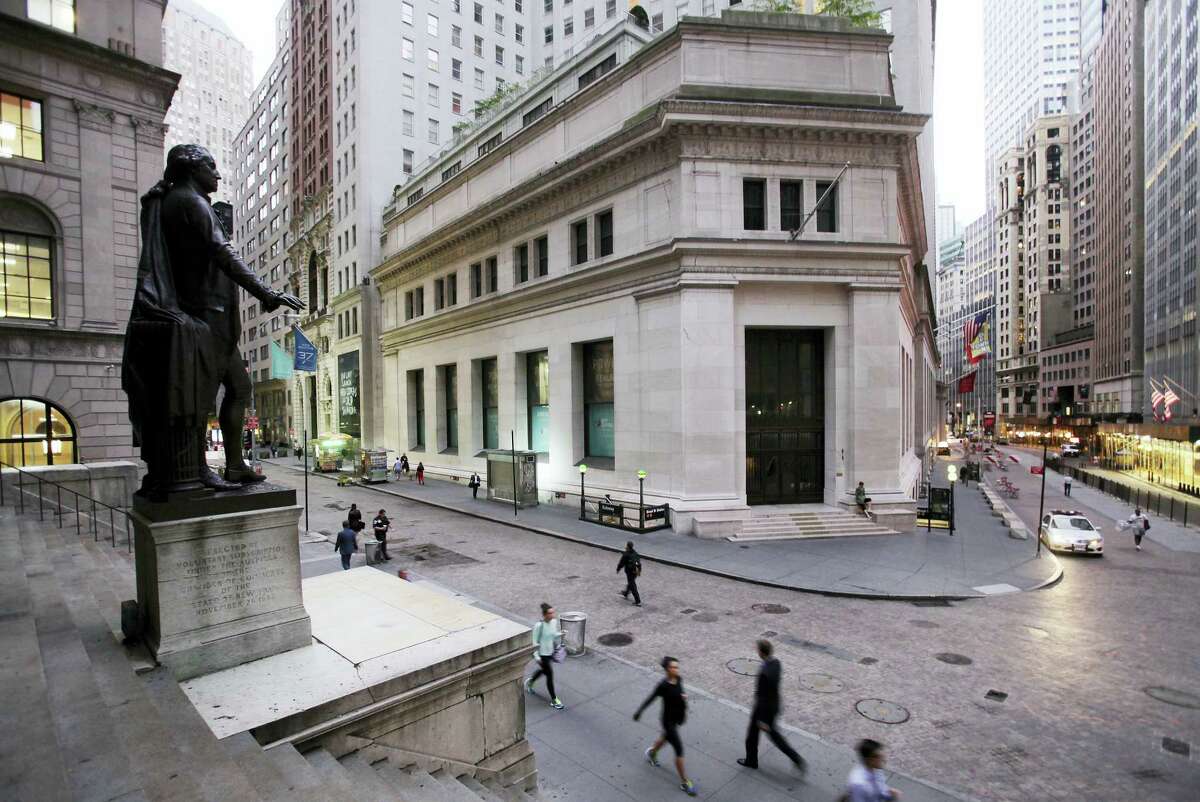 People walk to work on Wall Street beneath a statue of George Washington in New York.
