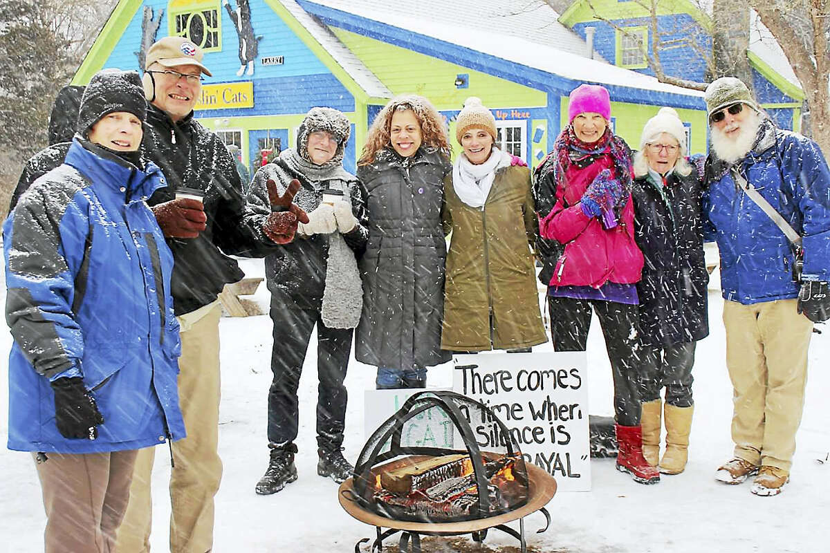 “There comes a time when silence is betrayal” says a sign near Together We Rise Building Bridges for Justice members warming up by a fire as snow falls at a recent vigil outside Two Wrasslin’ Cats in East Haddam.