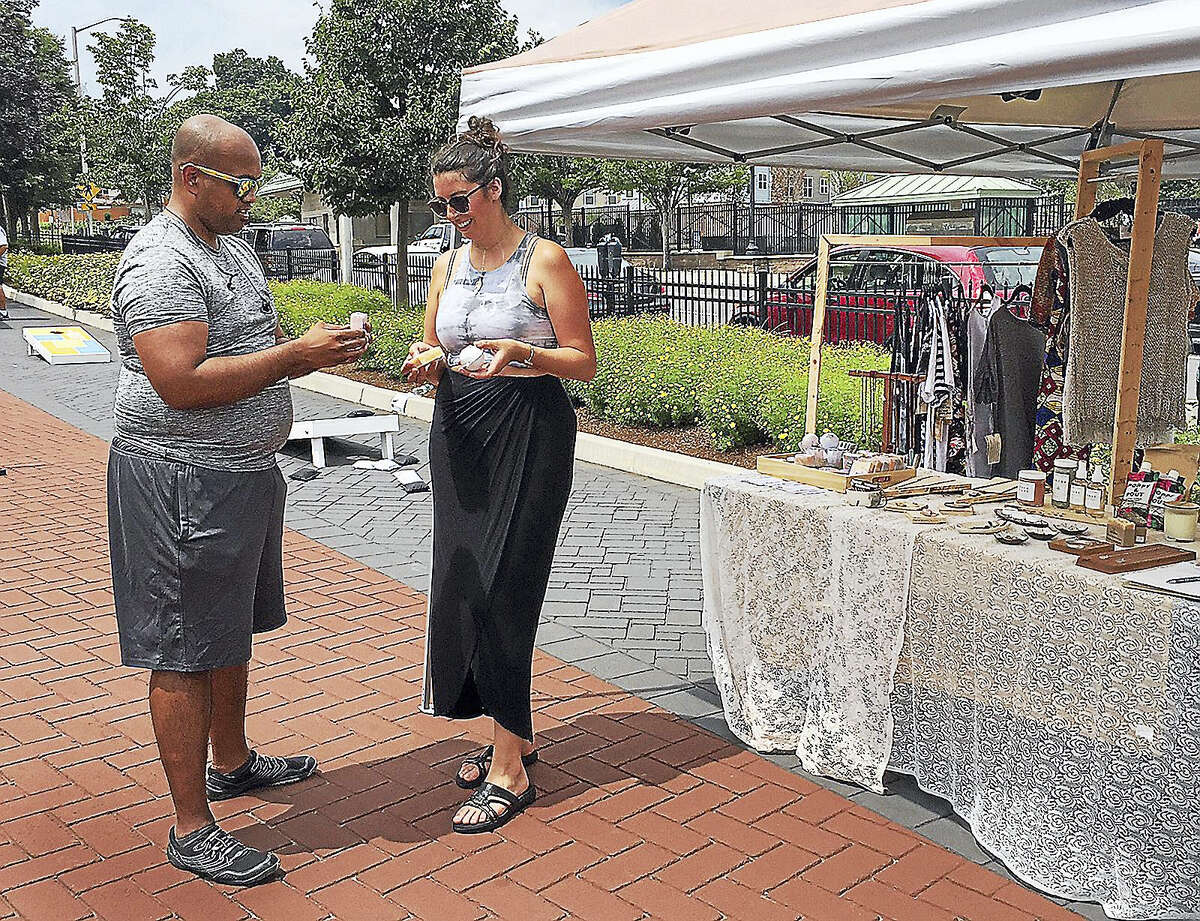 Meagan Cann of Workspace Collective shows handmade soaps to Joseph Purayidthil during the Downtown Chow-Down in Danbury Thursday.