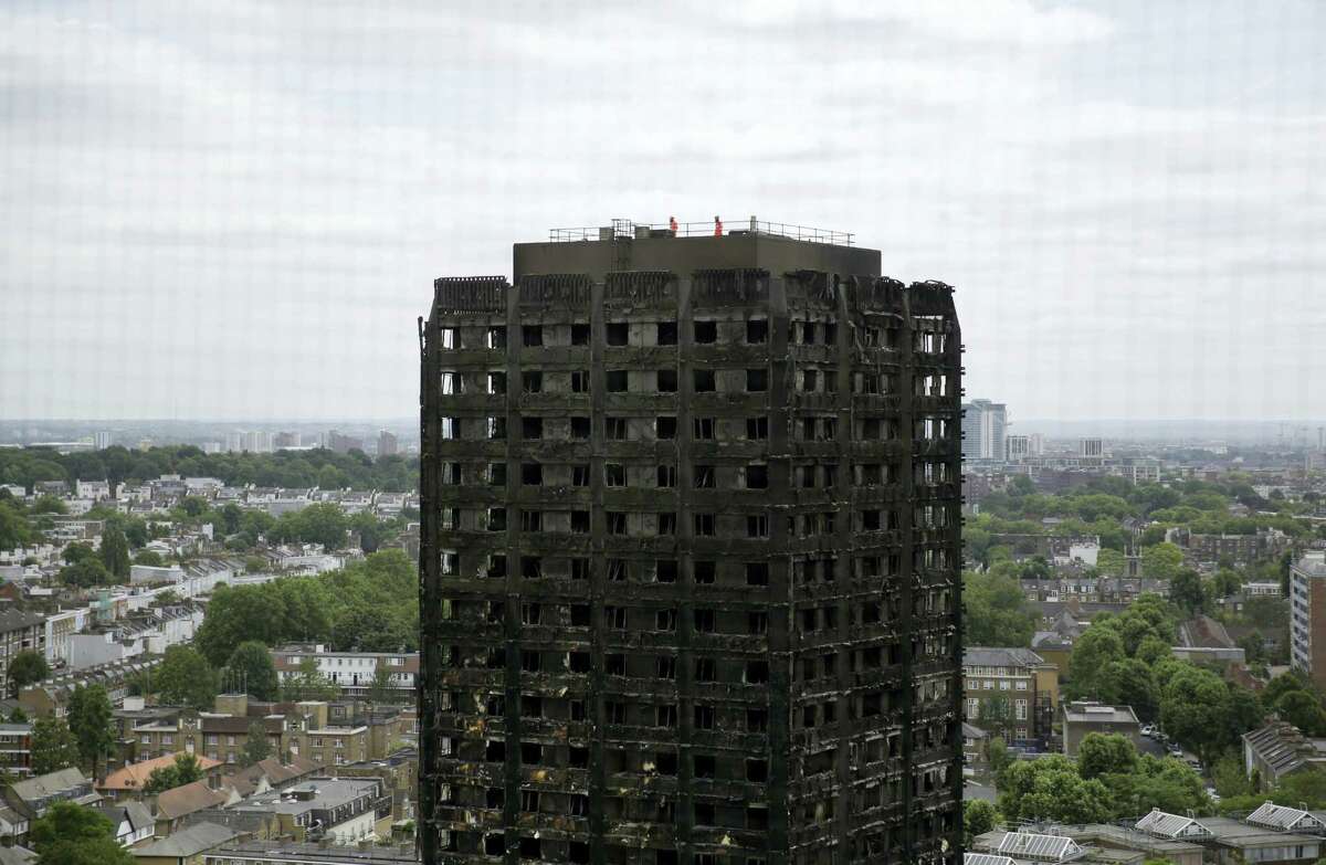 Emergency workers walk on the roof of the fire-gutted Grenfell Tower in London, Friday, June 16, 2017, after a fire engulfed the 24-storey building on Wednesday morning. Grief over a high-rise tower blaze that killed dozens of people turned to outrage Friday amid suggestions that materials used in a recent renovation project may have contributed to the disaster.