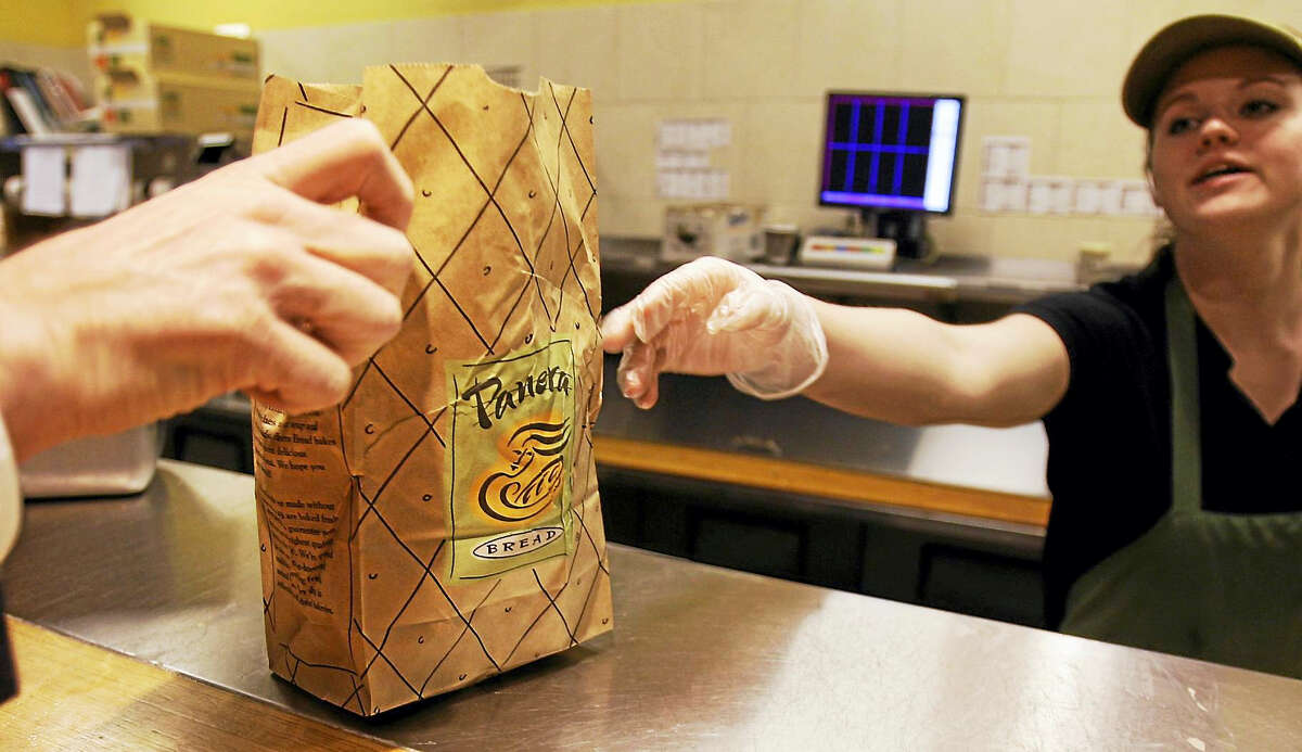 An employee passes an order to a customer at the Panera store in Brookline, Mass.