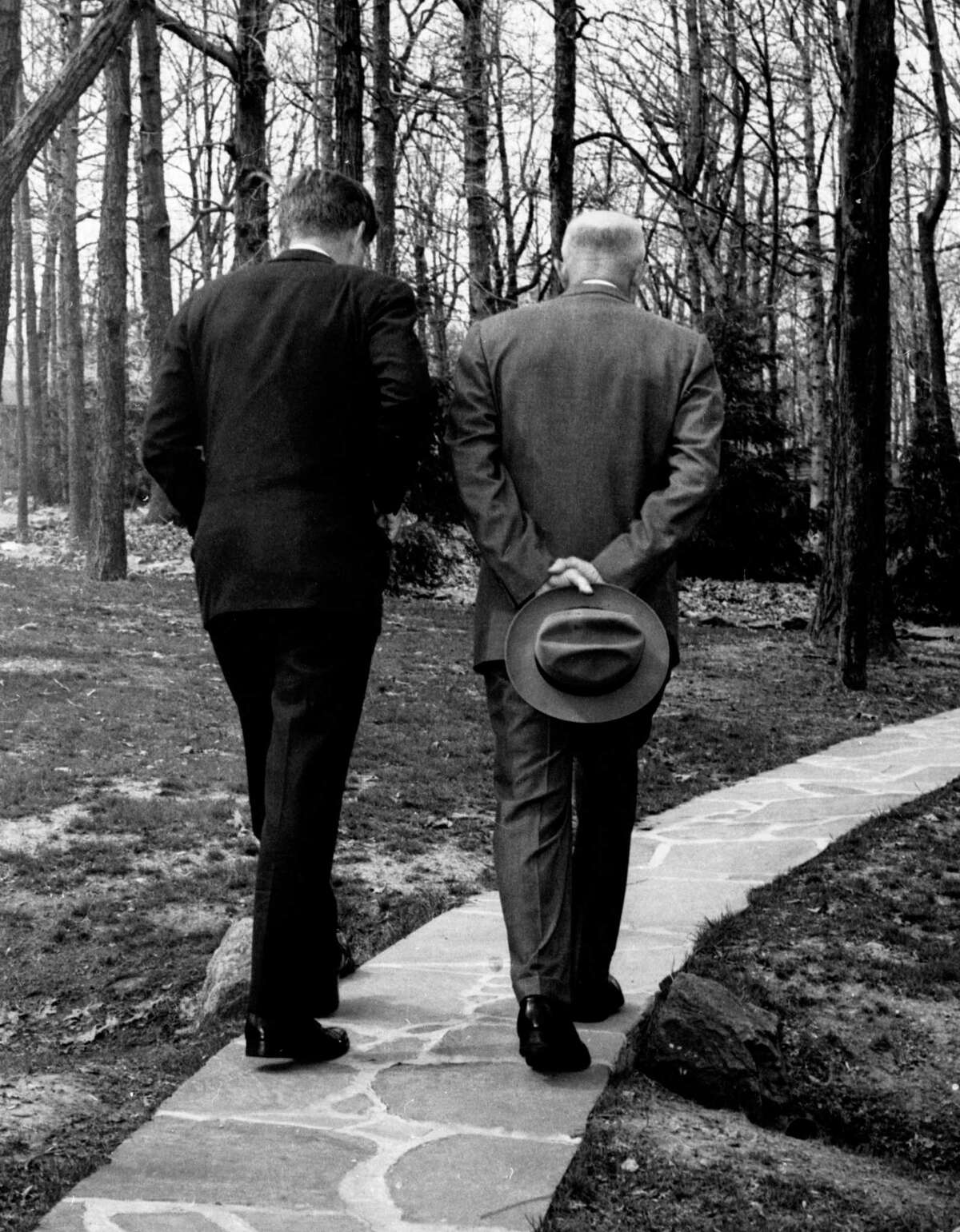 President John F. Kennedy, left, and former President Dwight D. Eisenhower with their heads bowed as they walk along a path at Camp David in Thurmond, Md.