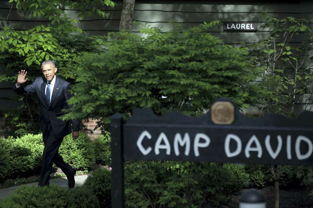FILE - In this May 14, 2015, file photo, President Barack Obama waves to members of the media after meeting with Gulf Cooperation Council leaders and delegations at Camp David, Md. President Donald Trump is picking simple over swanky this weekend. Nearly five months into his presidency, Trump is heading to Camp David, the government-owned retreat in Maryland’s Catoctin Mountains, for the first time. A frequent weekend traveler, Trump has so far favored his palatial residences in Florida and New Jersey over the wooded hideaway used by many presidents for a break from Washington.