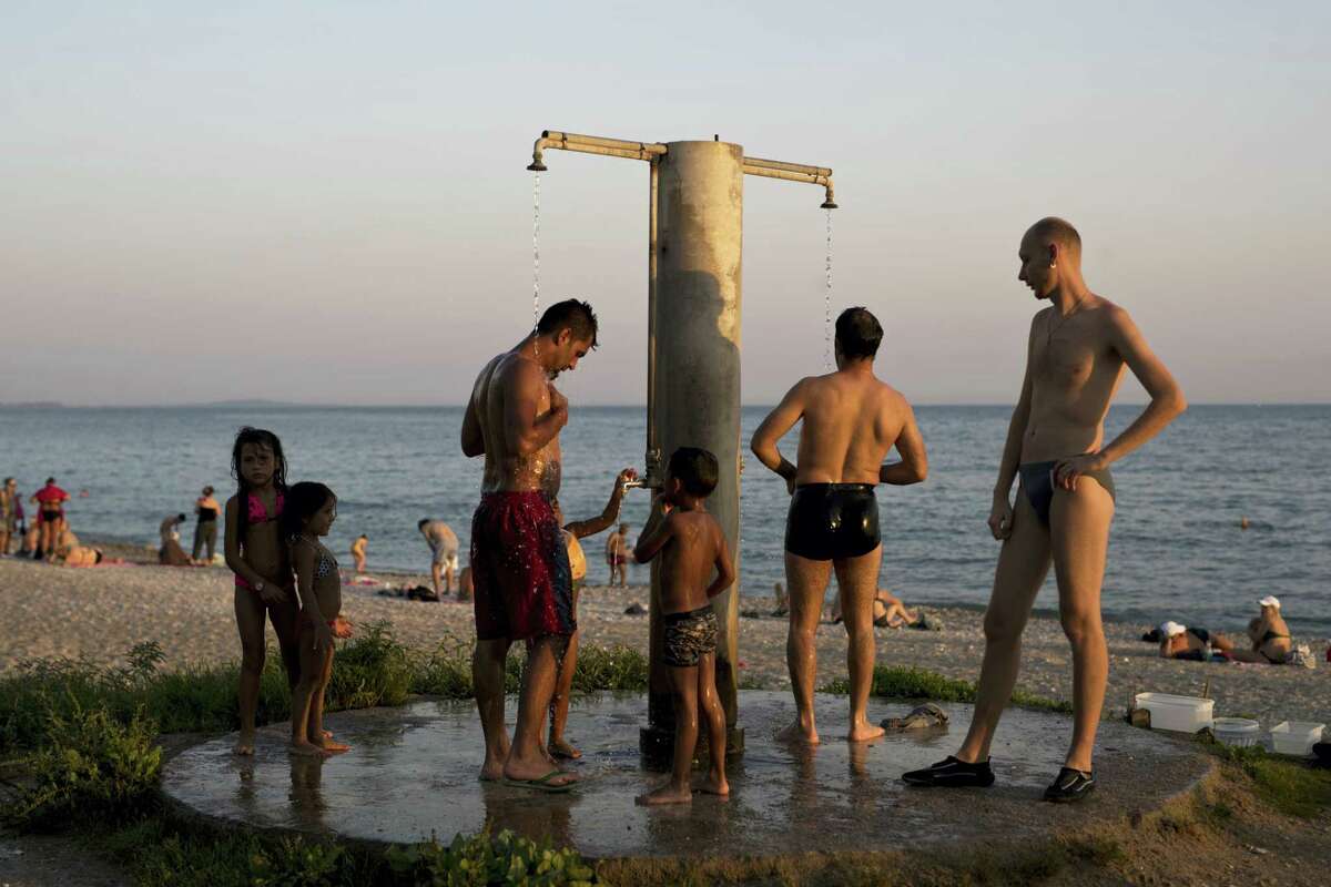 People take a shower at a beach of Alimos suburb, in Athens, Wednesday, July 12, 2017. A summer heatwave has hit Greece, with temperatures reaching a high of 39 degrees Celsius (102 Fahrenheit) in Athens.