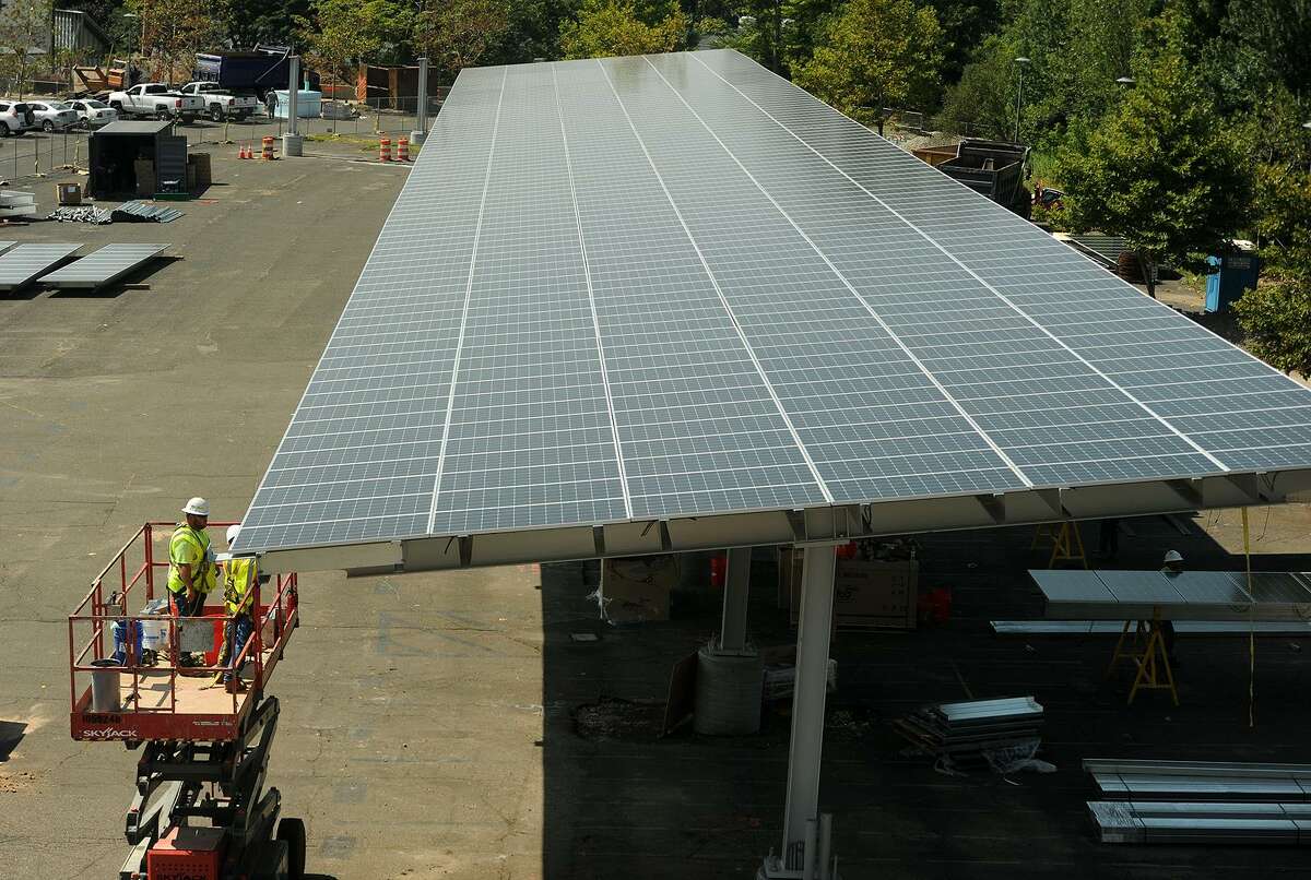 Workers install massive solar power iarrays above the student parking lot at Fairfield Ludlowe High School in Fairfield, Conn. on Thursday, August 10, 2017. An identical project is being undertaken at Fairfield Warde High School.