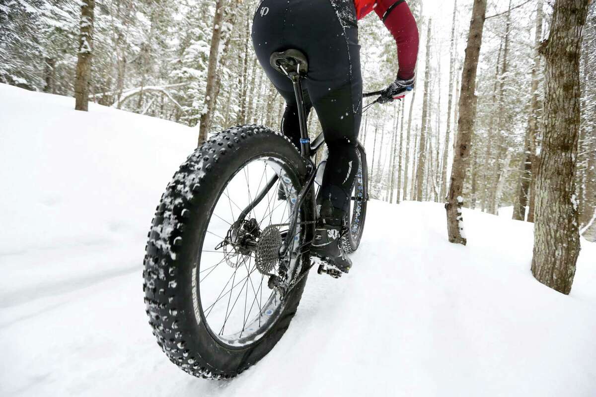 In this Saturday, Feb. 11, 2017, photo a fat tire bicyclist rides on a cross country ski trail during a race at the Sugarloaf ski resort in Carrabassett Valley, Maine. Gone are the days when cyclists had to hang up their bikes the winter. These days, many of them are grinding through winter’s snow and spring’s mud thanks to trendy new “fat bikes” with extra wide tires.