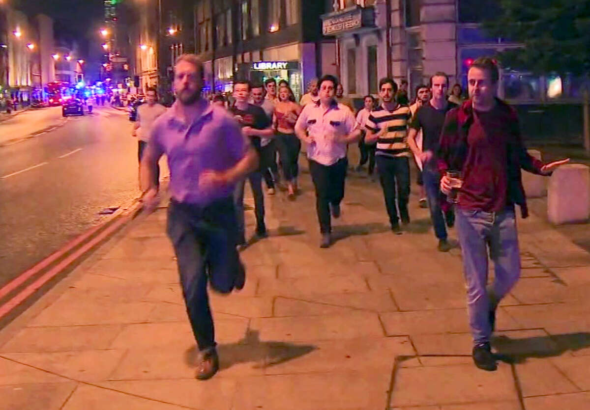 In this image taken from video footage, people run from the scene of attack, alongside a man strolling holding a pint of beer, right, in London, late Saturday, June 3, 2017. People in the U.K. have responded to the deadly London Bridge attack with sorrow and distinctly British humor, hailing a man pictured walking away from the mayhem holding a pint of beer as a tongue-in-cheek symbol of defiance. (Sky news via AP)