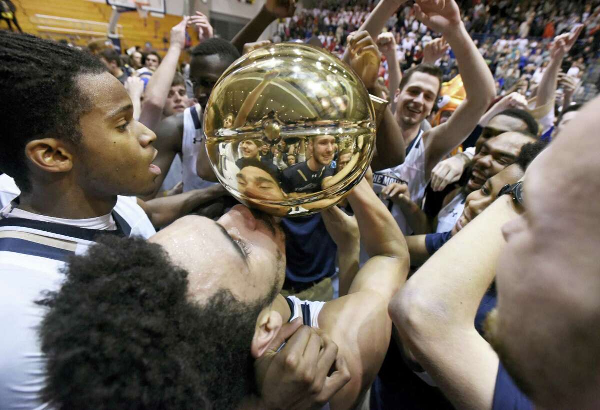 Mount St. Mary’s guard Elijah Long, center, kisses the Northeast Conference Tournament championship trophy after beating St. Francis (Pa.) 71-61 in the Northeast Conference Tournament championship game Tuesday.