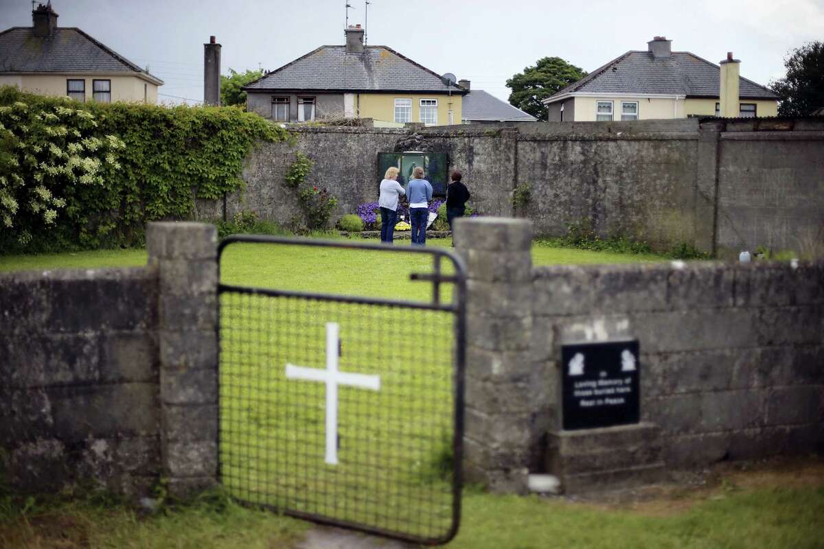 In this June 7, 2014, file photo members of the public at the site of a mass grave for children who died in the Tuam mother and baby home, in Tuam, County Galway. Forensics experts say they have found a mass grave for young children at a former Catholic orphanage in Ireland where suspicions of unrecorded, unmarked burials have lingered for decades.