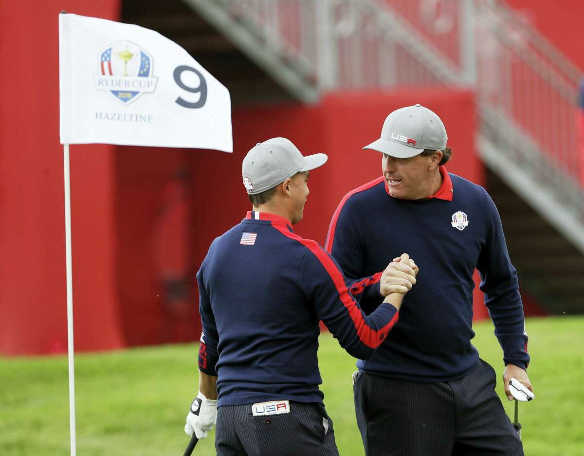 Phil Mickelson celebrates with teammate Rickie Fowler after Fowler chipped in on the ninth to win the hole during the Ryder Cup on Friday.