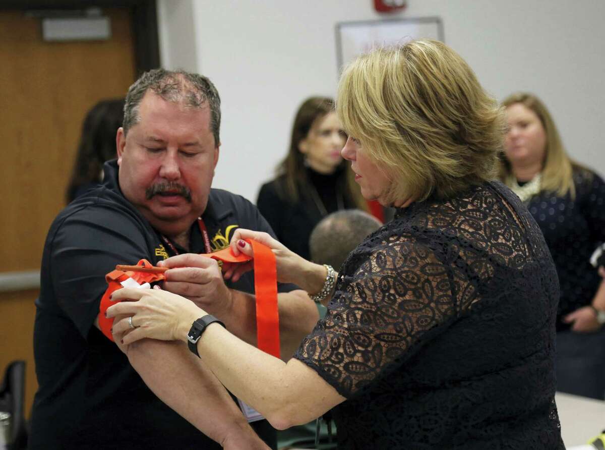 Two staffers from the Three Village Central School District in Stony Brook, N.Y., practice applying a tourniquet to one another during a first aid training session at Stony Brook University, Tuesday in New York. A new federal initiative seeks to prevent deaths in terror attacks and school shootings by training ordinary people from custodians to administrators on how to treat gunshots, gashes and other injuries. Stony Brook doctors have reached out to local schools to offer the training, but are looking to expand the program as part of a federal Department of Homeland Security initiative to other schools, colleges and police departments across the country.