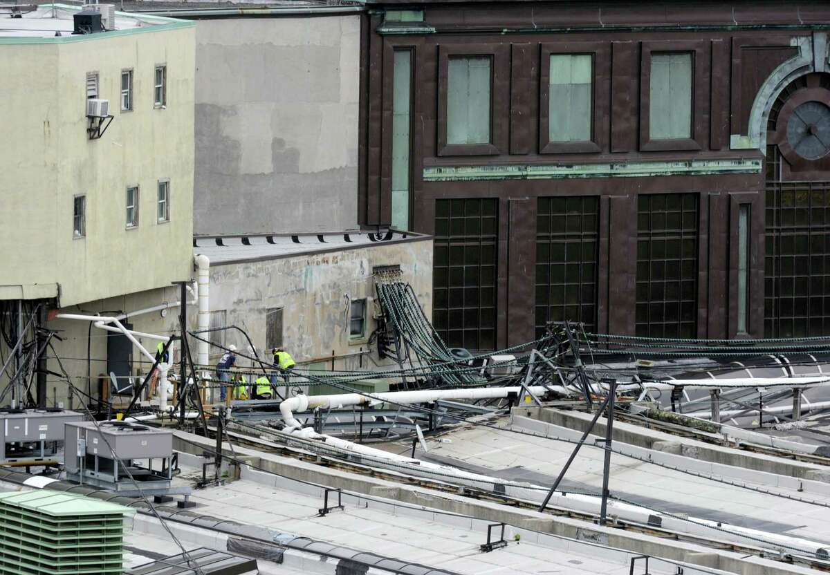 Workers examine a section of the roof at the Hoboken station where a train crashed into the building, Thursday Sept. 29, 2016 in Hoboken, N.J. A rush-hour commuter train crashed through a barrier at the busy Hoboken station and lurched across the waiting area Thursday morning, killing one person and injuring more than 100 others in a tangle of broken concrete, twisted metal and dangling wires.