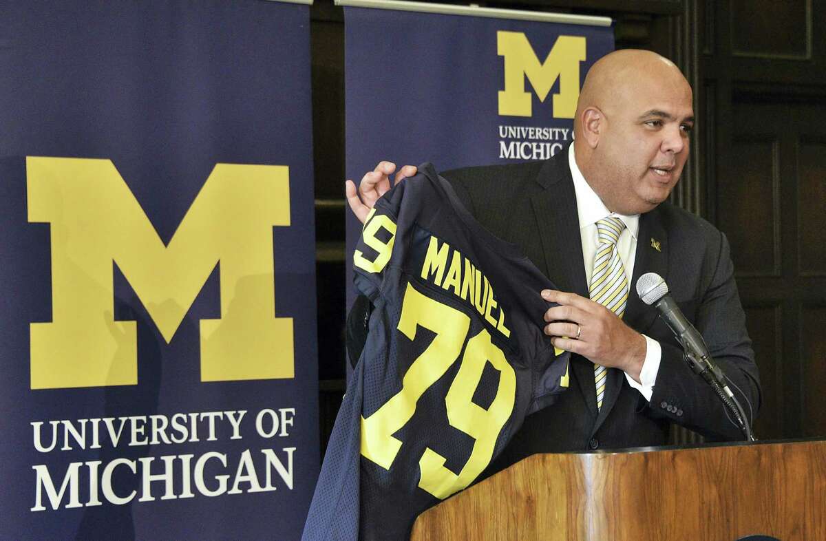 Michigan’s new athletic director Warde Manuel holds up a jersey during a news conference Friday at the Student Union in Ann Arbor, Mich. The 47-year-old Manuel, who had been UConn’s athletic director since 2012, was given a five-year deal by Michigan.