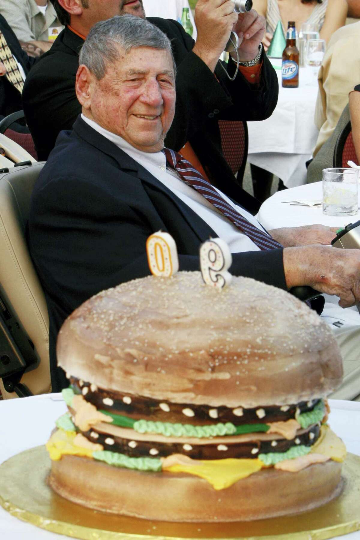 In this file photo, Big Mac creator Michael “Jim” Delligatti sits behind a Big Mac birthday cake at his 90th birthday party in Canonsburg, Pa. Delligatti, the Pittsburgh-area McDonald’s franchisee who created the Big Mac in 1967, has died. He was 98.