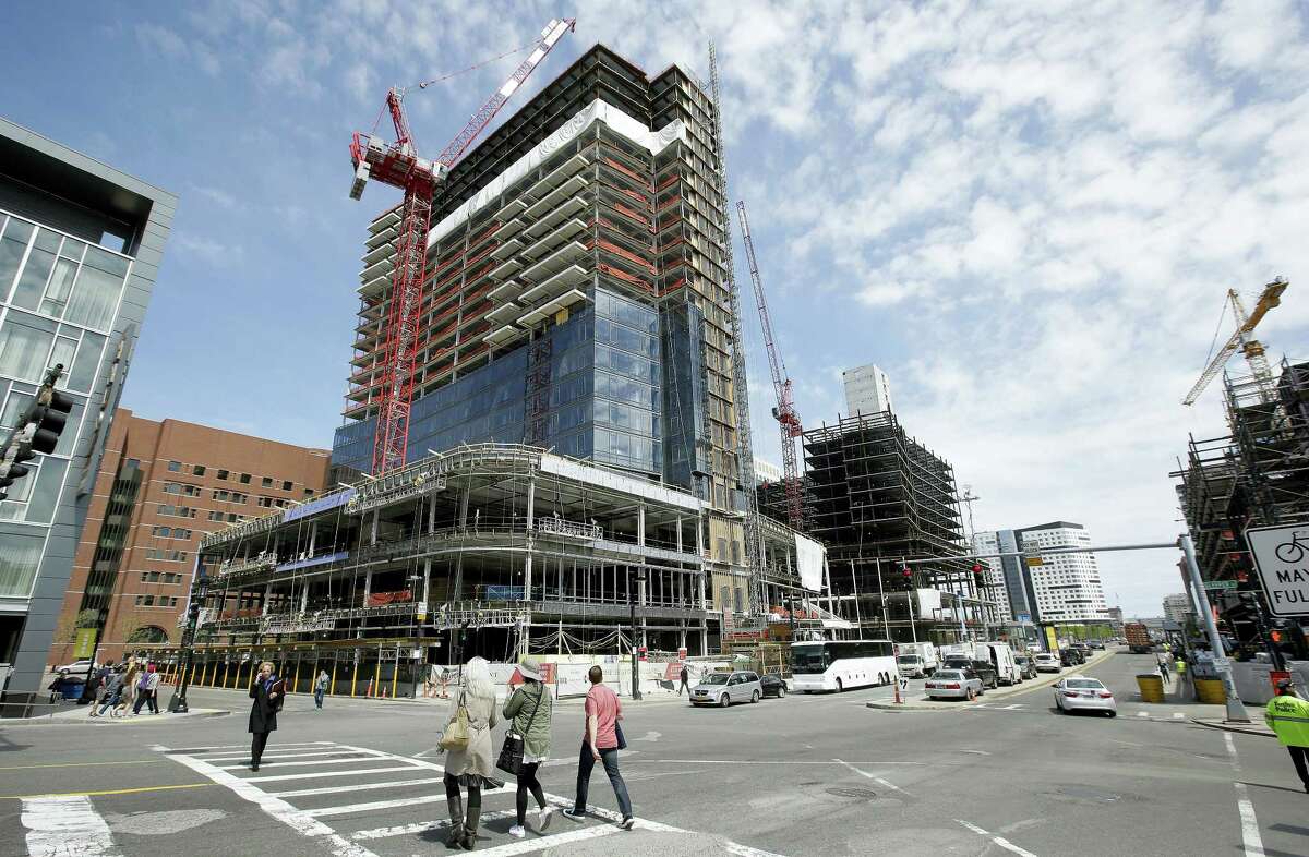 In this Thursday, May 19, 2016, file photo, passersby walk near the construction site of a high-rise building in Boston. On Friday, July 29, 2016, the Commerce Department issued the first estimate of how the U.S. economy performed in the April-June quarter. It was generally disappointing.